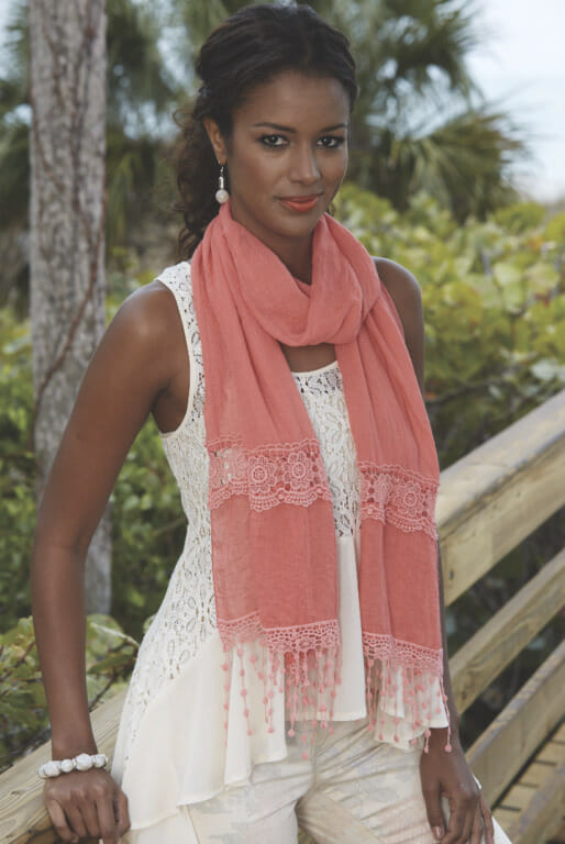 Especially during early and late summer when the mornings and evenings are a little breezy, scarves make the perfect chic accessory. Woman in coral scarf over white lace tank and white pants