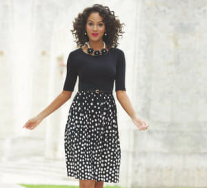 Woman in dress with solid black on top and black and white dotted on bottom