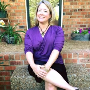 woman seated wearing aubergine top and black skirt