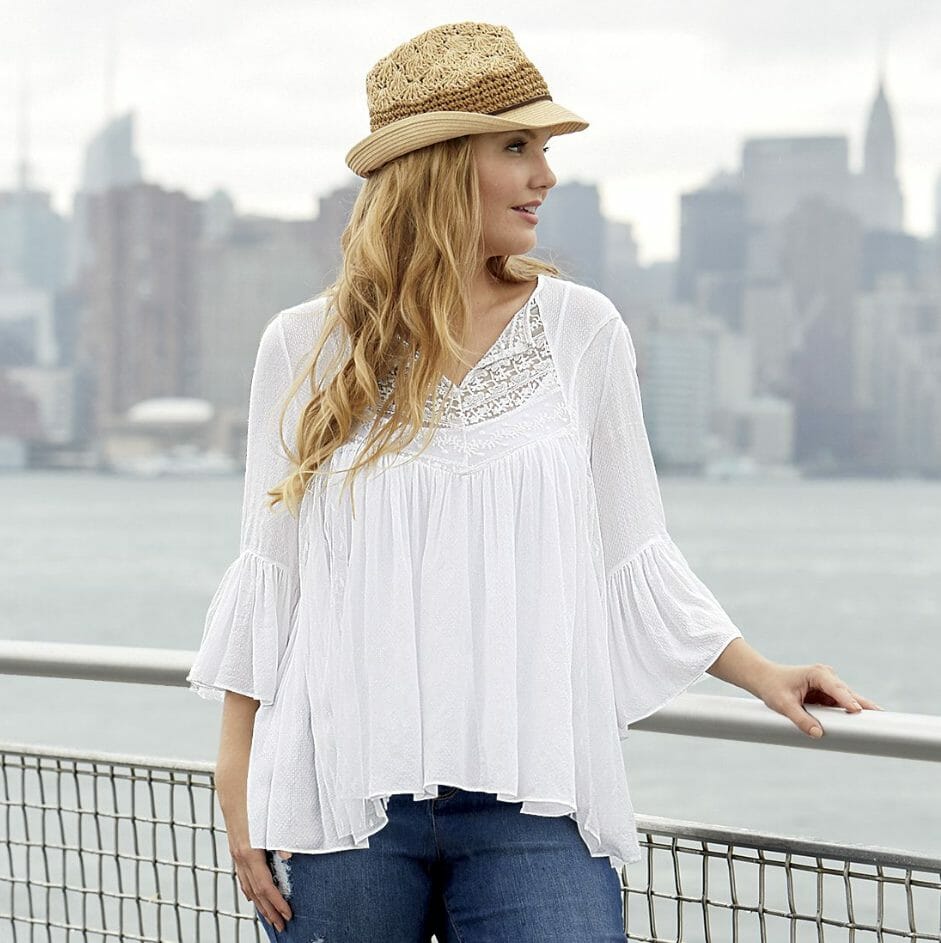 Woman in jeans and white, empire waisted blouse with bell sleeves
