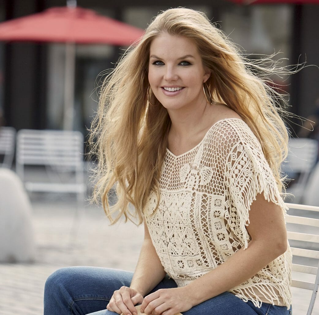 Woman in jeans and boho-fringed, crochet poncho over a beige tank top