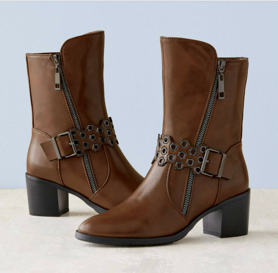Stylish brown ankle boots with a side zipper and decorative buckle detail, set against a light blue background.