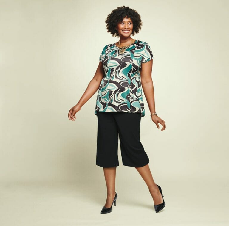 plus size model wearing a blue printed shirt with black capris.