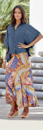 Woman in denim poncho-styled top and multi-colored skirt and brown wedges