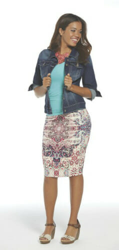 Woman in denim jacket over aqua top, multi-colored paisley print skirt and wedges