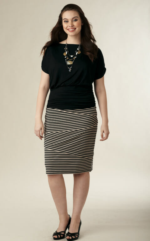 Woman in black ruched top, black striped skirt and black heels
