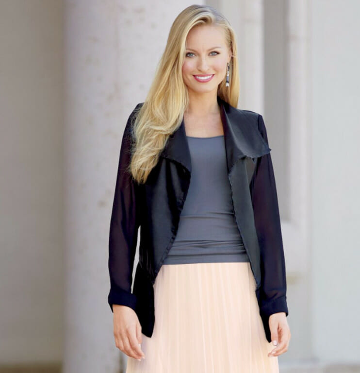 woman wearing black jacket over gray top and soft pink pleated skirt