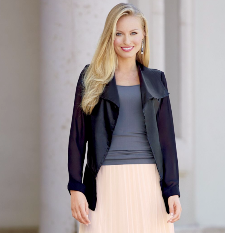 woman wearing black jacket over gray top and soft pink pleated skirt