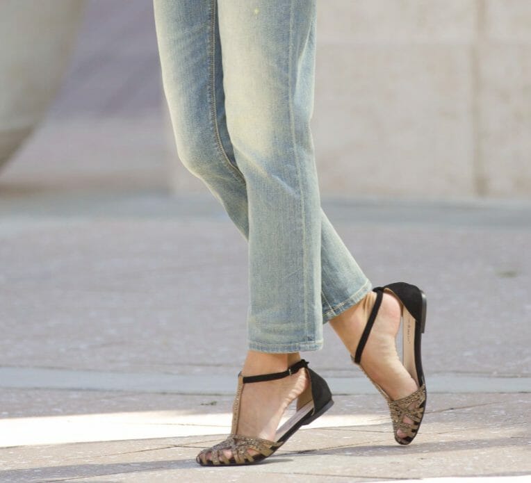 a woman wearing jeans with strappy sandals