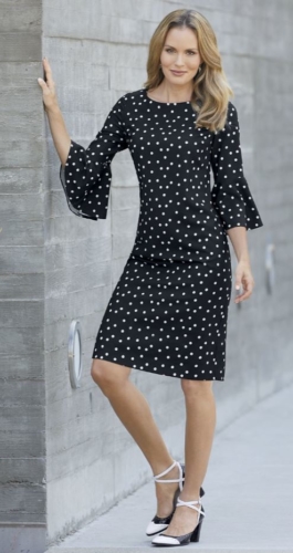 Woman in A-line, flounced bell sleeved, black and white polka dot dress with black and white heels