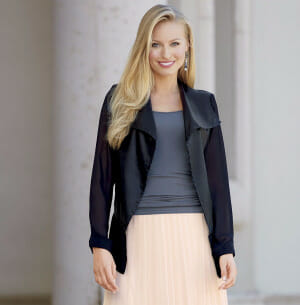 woman black jacket over gray top and soft pink pleated skirt