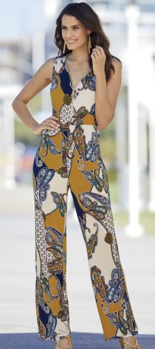 woman wearing multi colored paisley print jumpsuit with goldtone zipper down center and gold heels