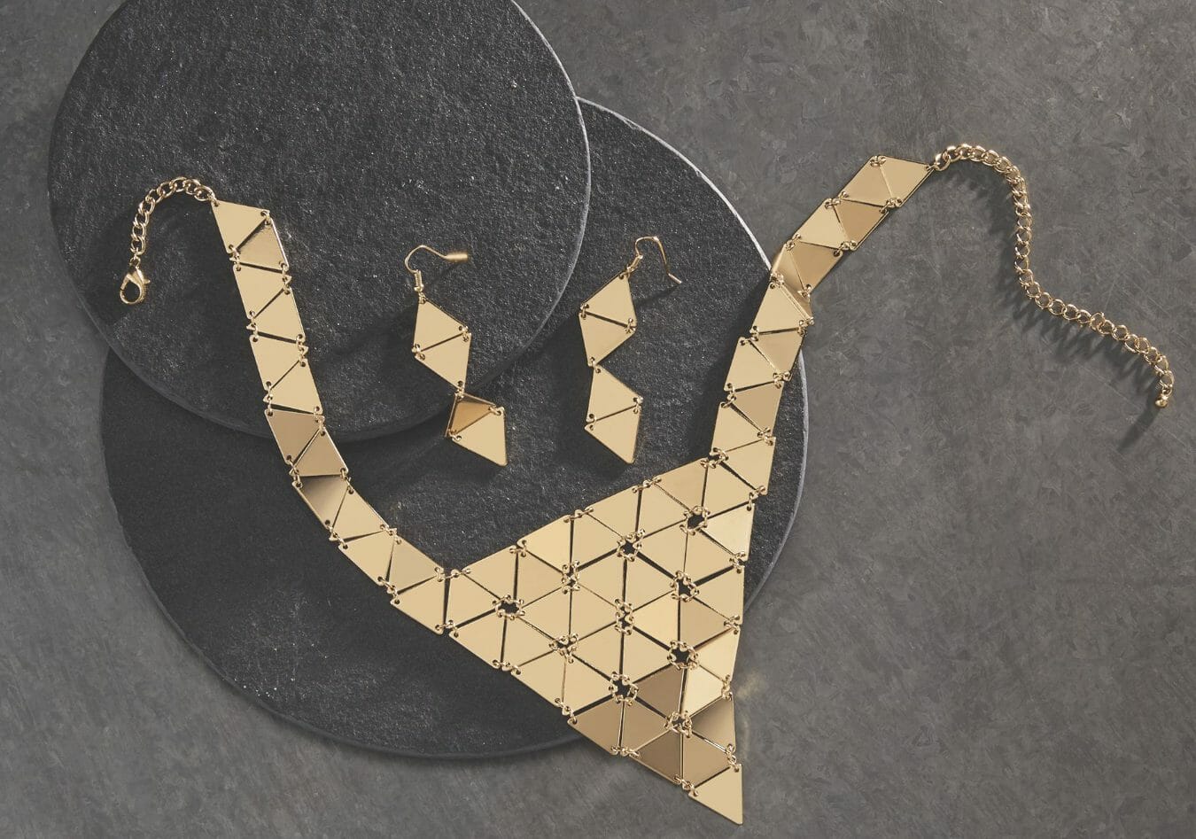 Triangles link together to create a bold geometric statement. Necklace is 18" long plus 3" extender. Earrings are 2 1/2" long. Available in goldtone, silvertone and gunmetal.