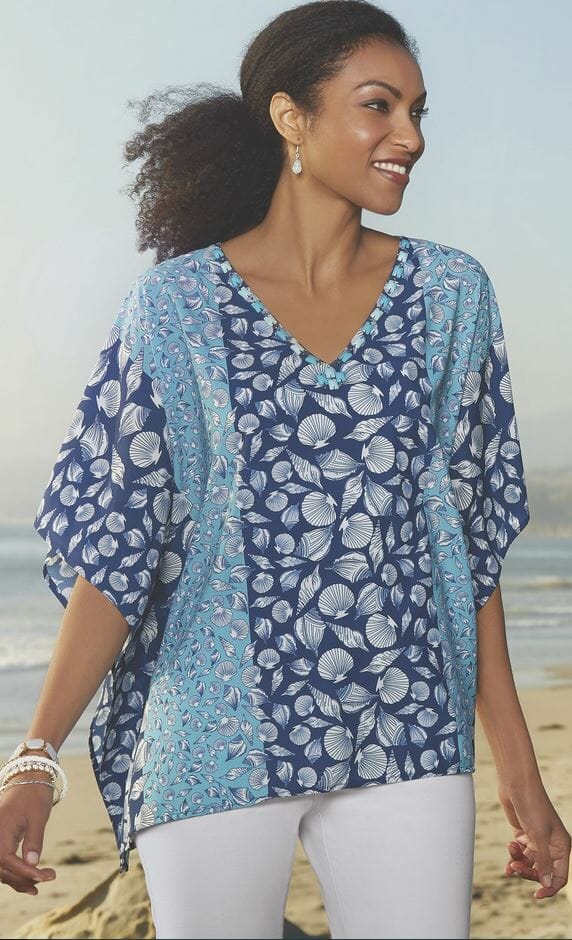 Woman in white pants and blue caftan with seashell pattern