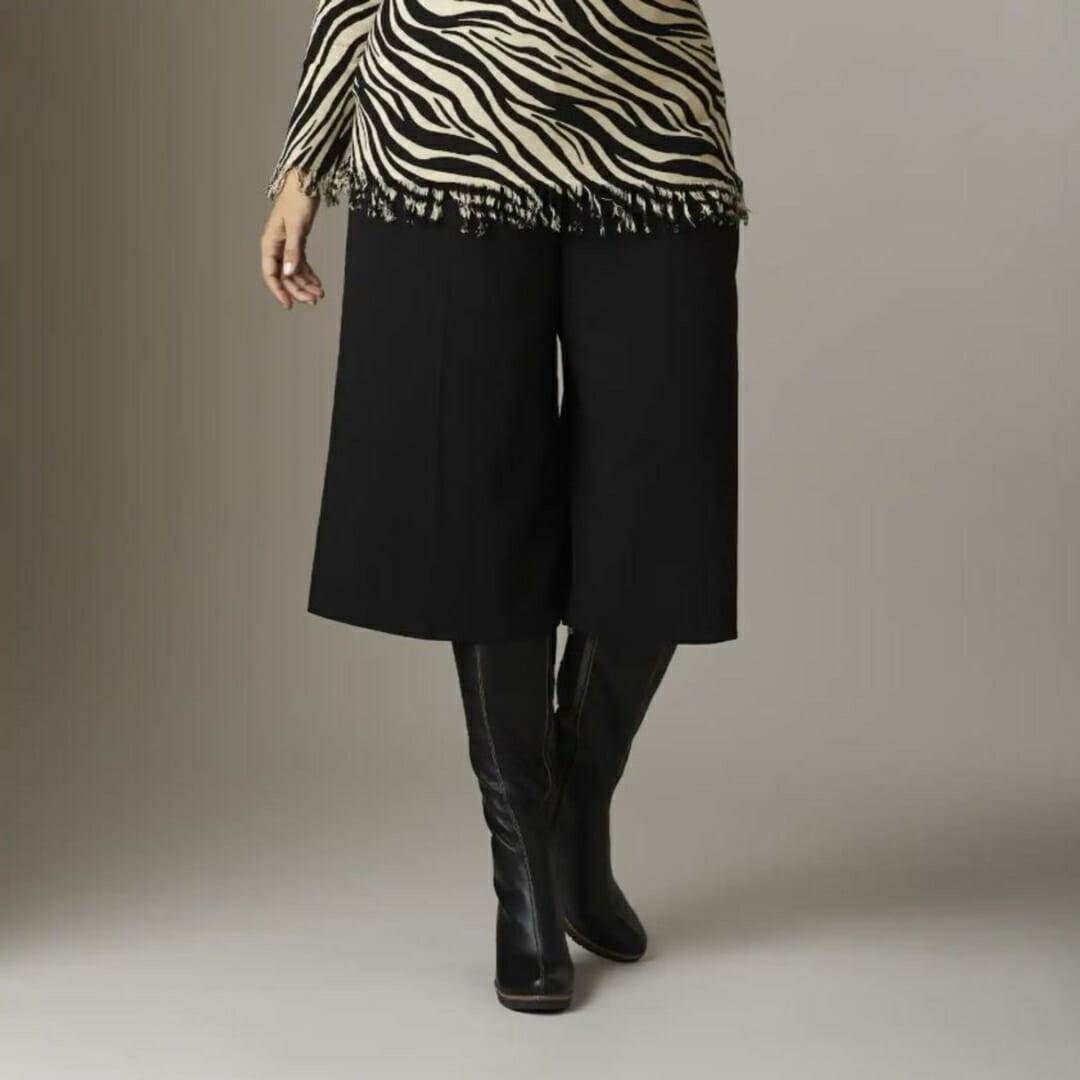 woman wearing black knee-high boots, black gaucho pants and zebra print top