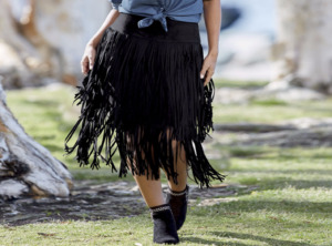 Woman in black booties, denim shirt and black fringed skirt
