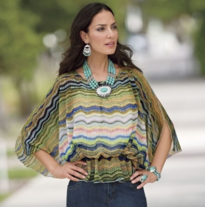 Woman in jeans and multi-colored, wavy lined pattern blouse with turquoise medallion necklace