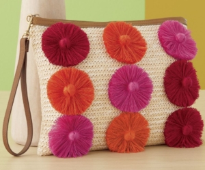 Raffia clutch adorned with brightly colored yarn flowers