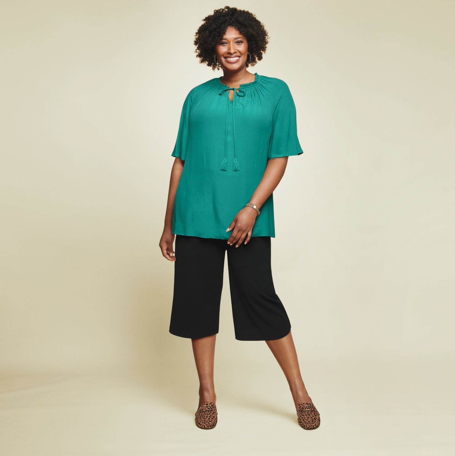 plus size model wearing a blue top with black capris.