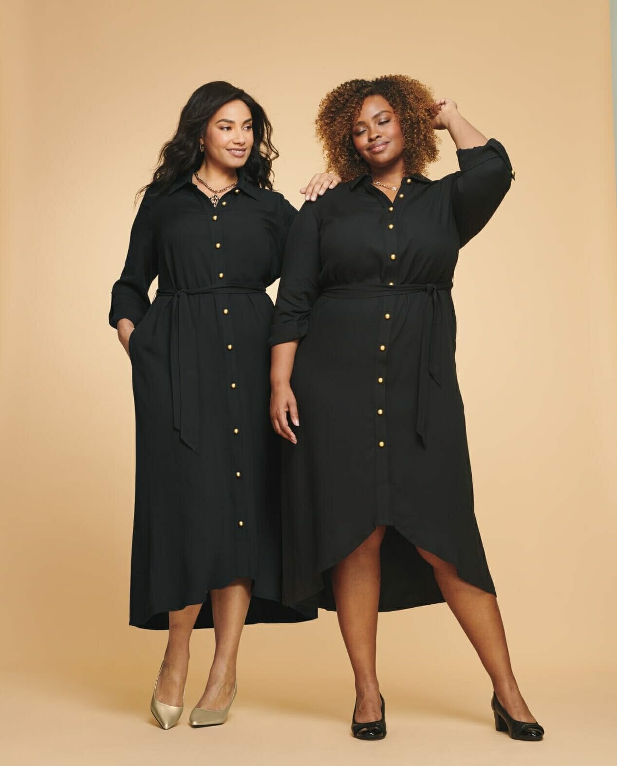 two plus-sized models wearing long sleeve black dresses.