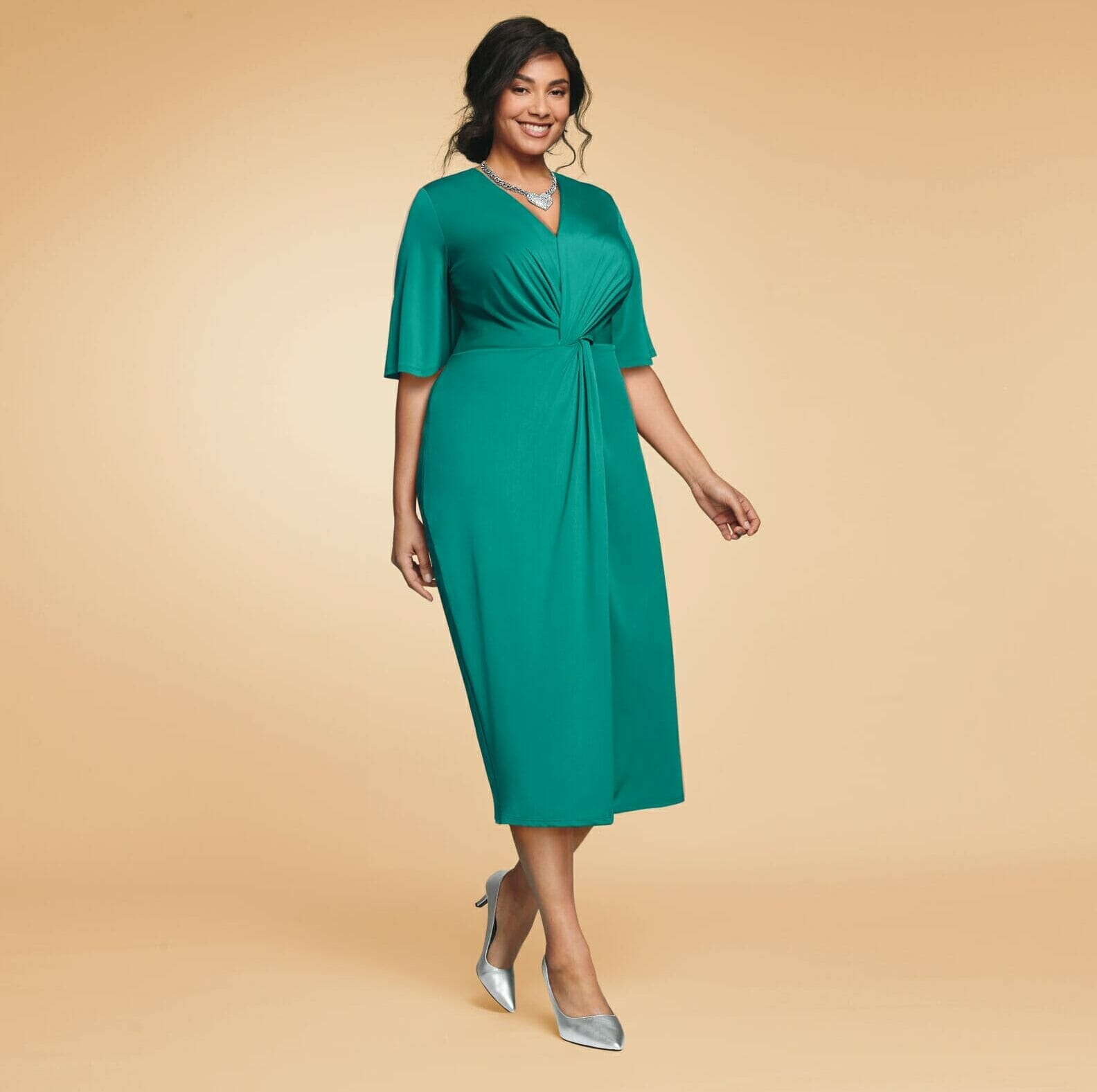Plus size model wearing sage colored dress.