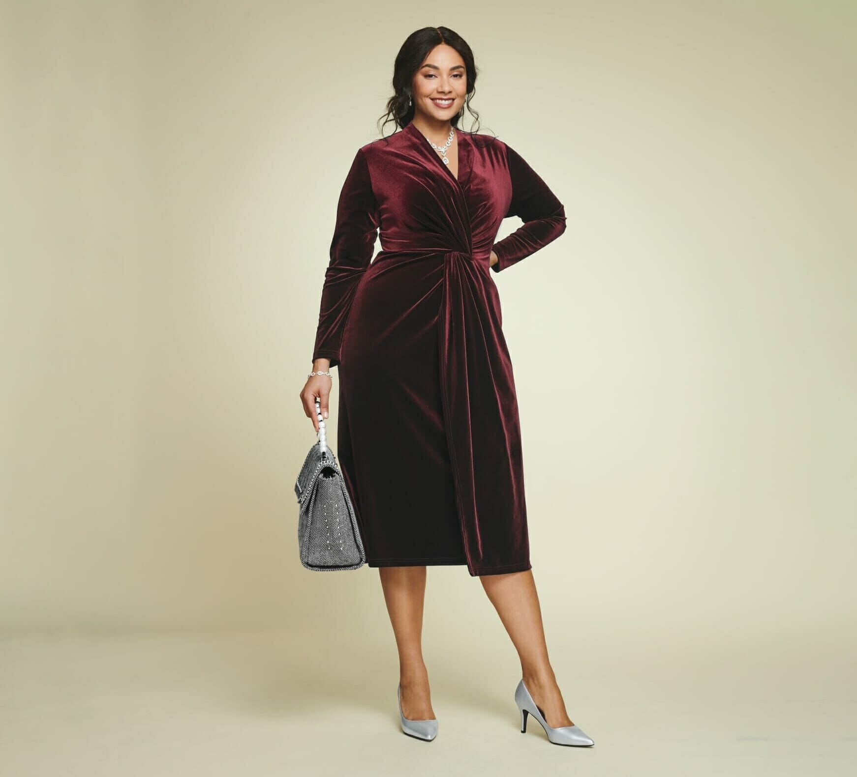 plus size model wearing a burgundy velvet dress with silver metallic pumps