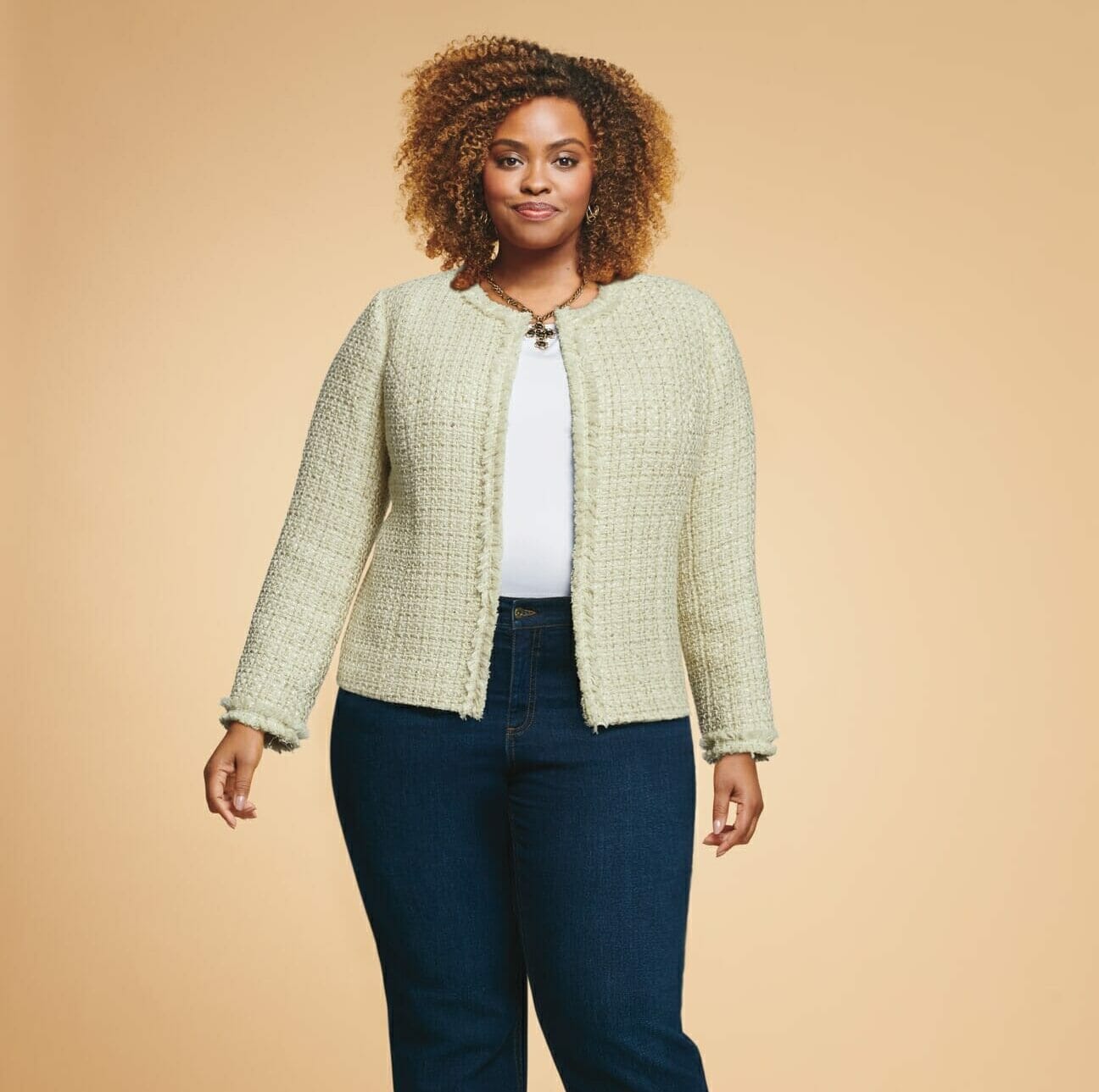 plus size model wearing a cream jacket with jeans.