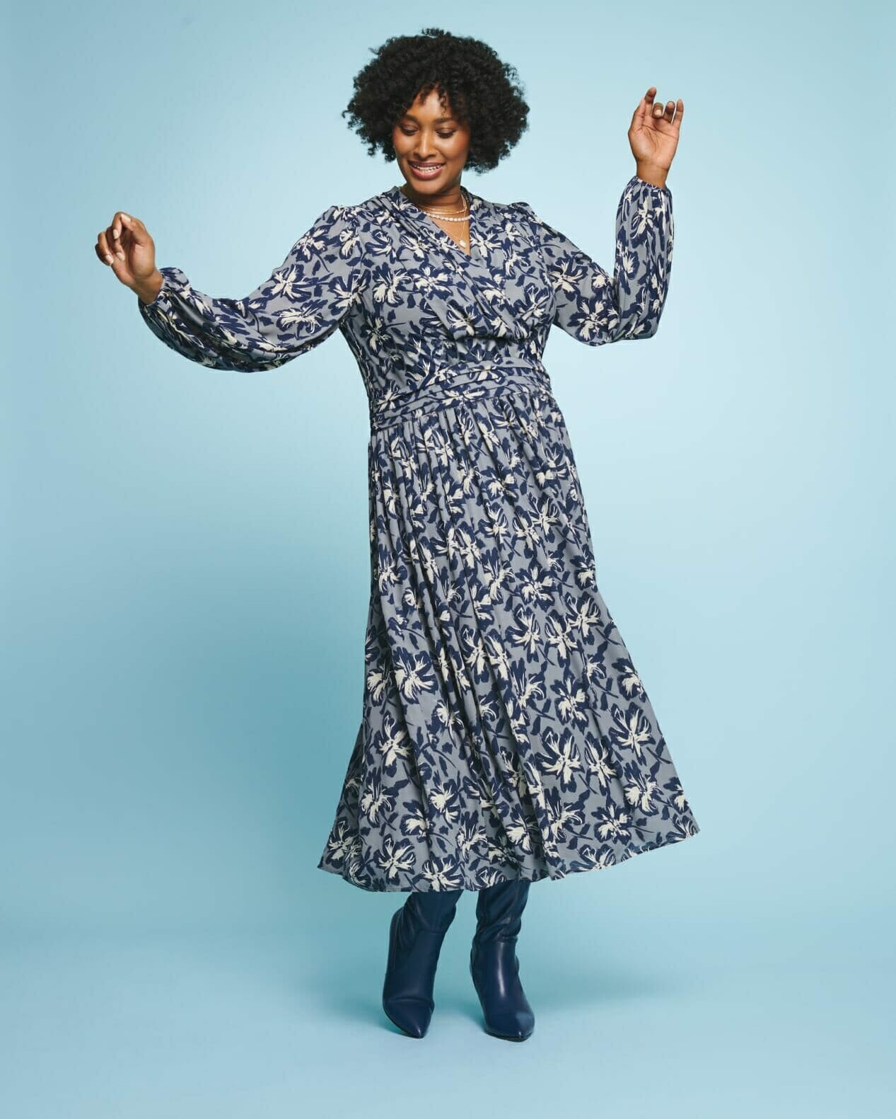 plus size model wearing a floral blue dress with boots.