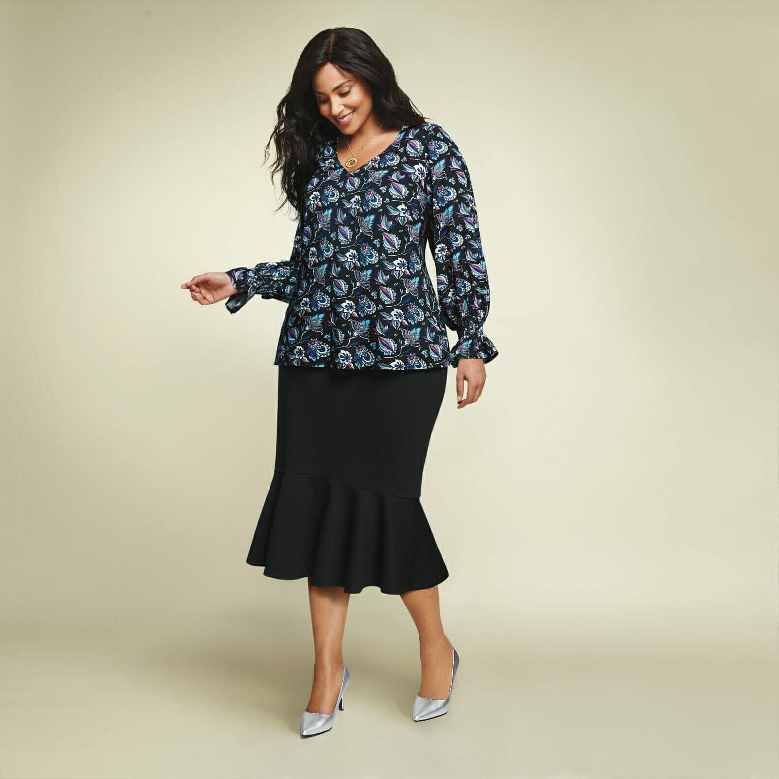 Plus size model wearing a long sleeve top with black skirt.