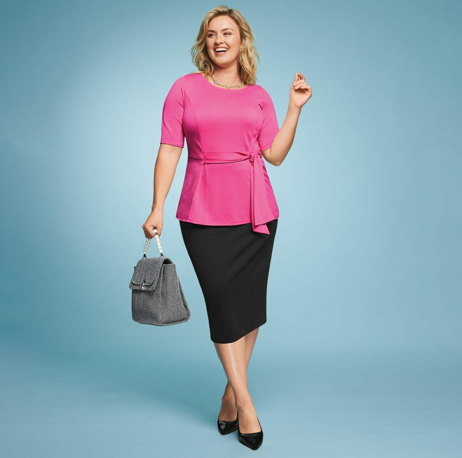 Plus size model wearing a pink top with a black skirt