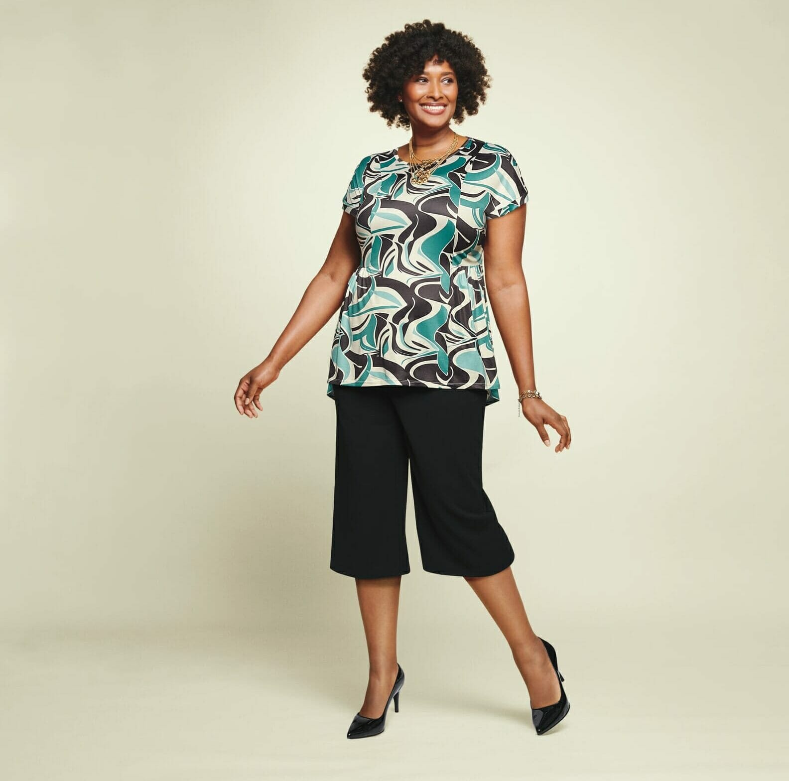 plus size model wearing a blue printed shirt with black capris.