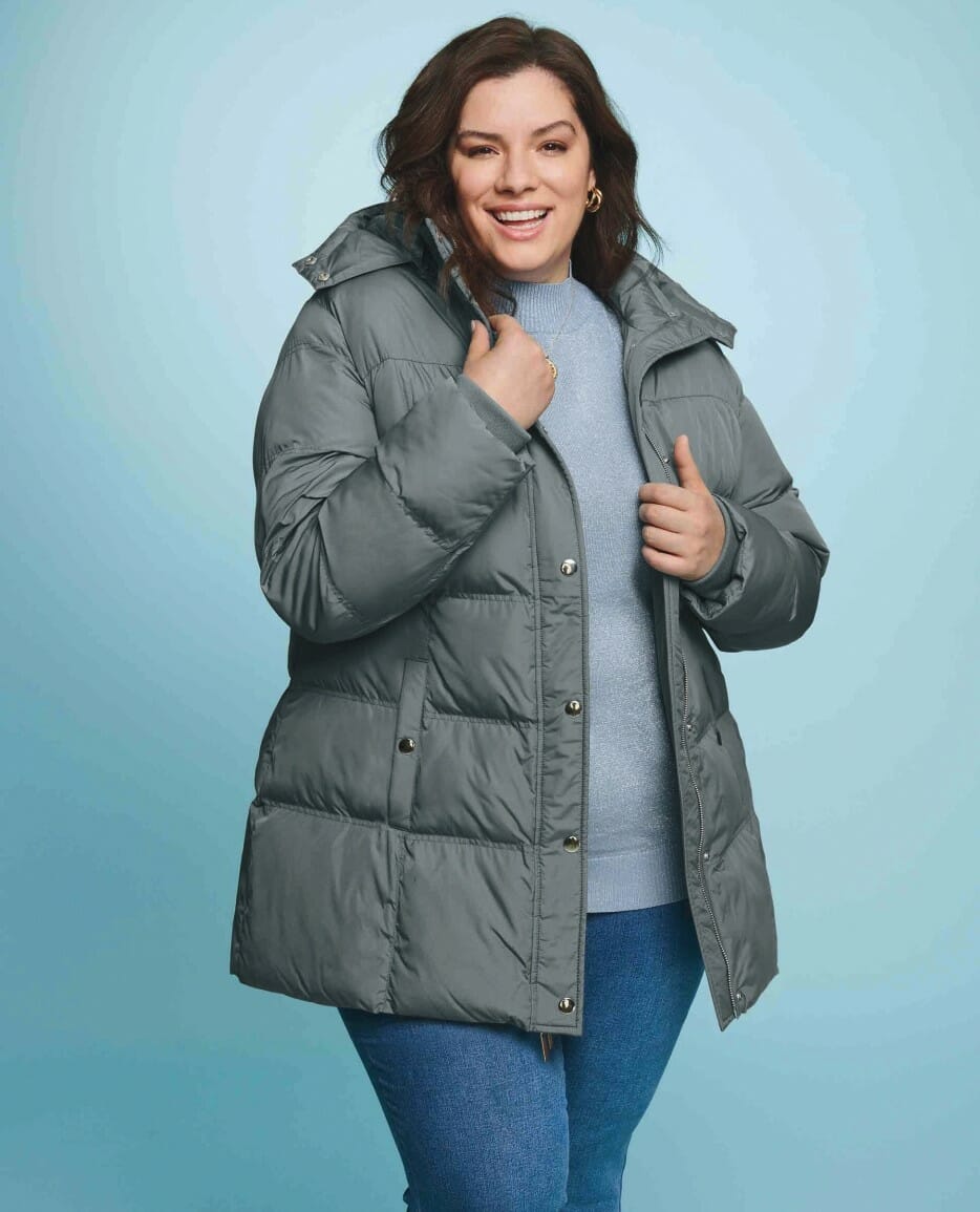 plus size model wearing a grey parka coat with jeans.