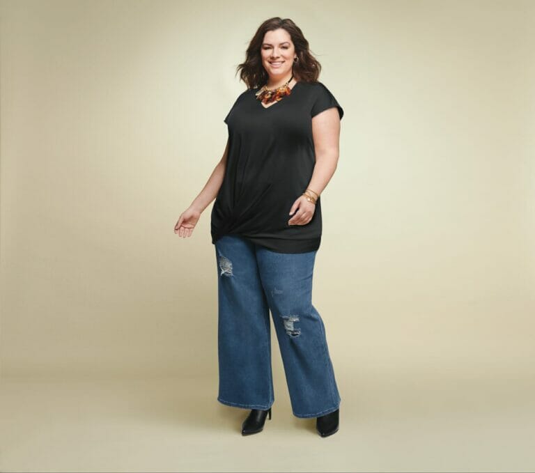Plus size model wearing a black top with distressed jeans.