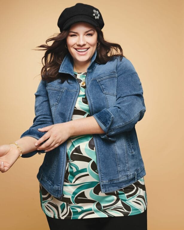 plus size model wearing a blue and black printed shirt with a jean jacket.