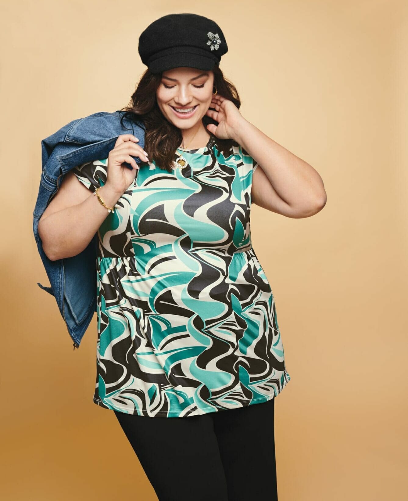 plus size model wearing a blue and black printed shirt with a black cap.