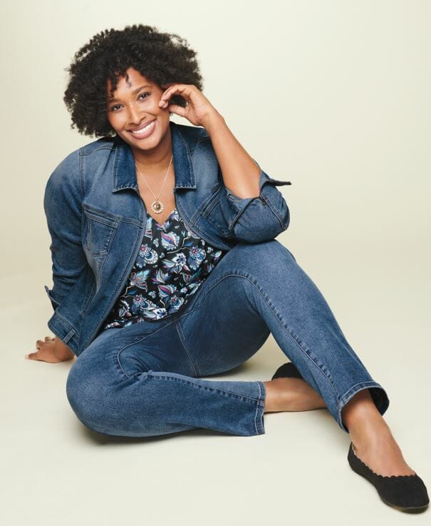 Black plus size model smiling wearing jean jacket and jeans