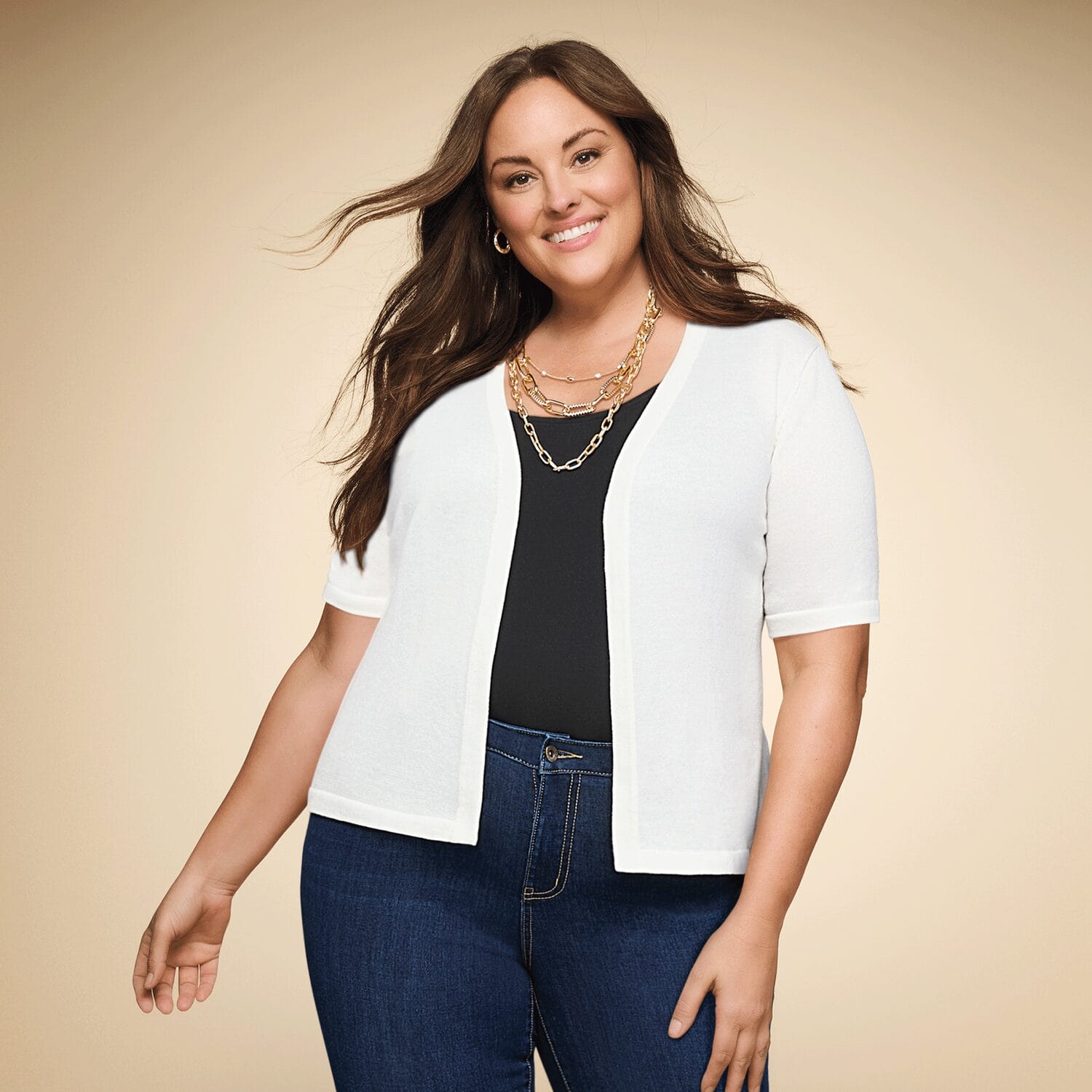 Plus size woman wearing a white short sleeve button sweater over a t-shirt and jeans.