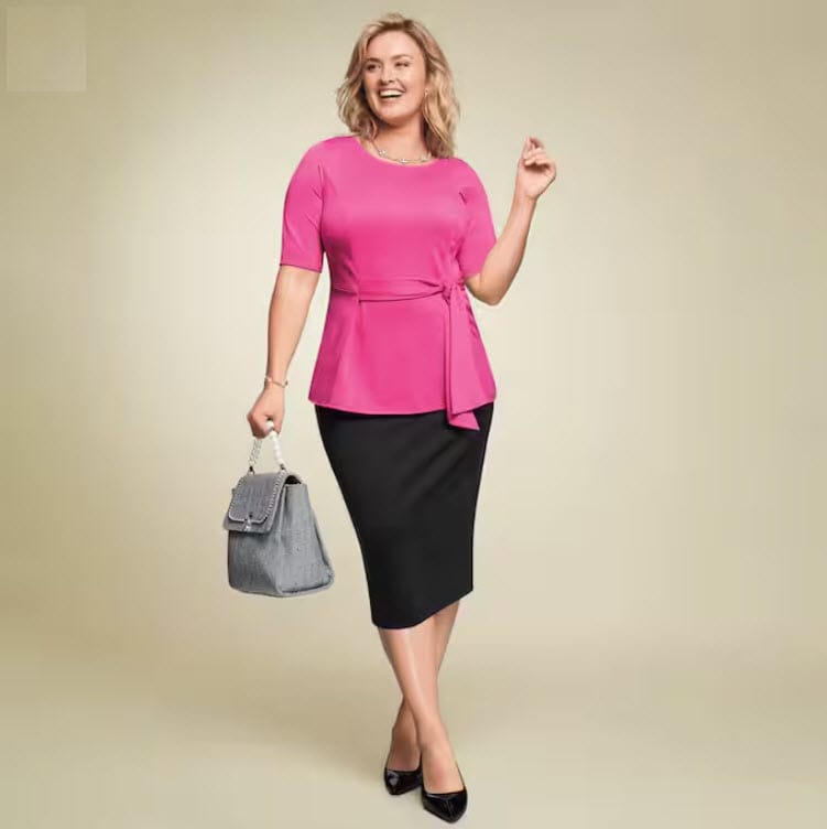 Plus size model in pink top black skirt, black pumps and silver purse