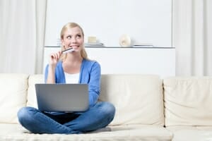 Woman sitting on couch with credit card and laptop